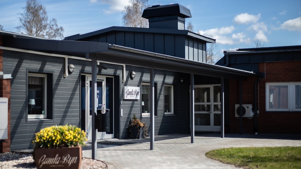 En grå byggnad med en skylt där det står "Gamla byn" på.
