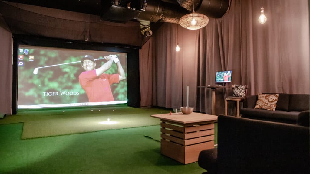 En man spelar golf på en storbildsskärm.
