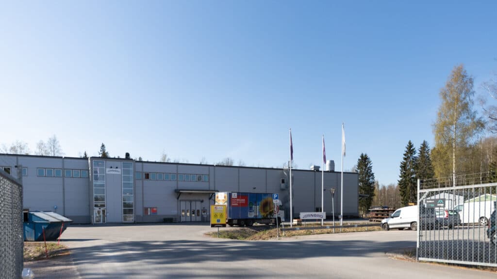 Grå industrifastighet med grindar till parkeringsplatser utanför.