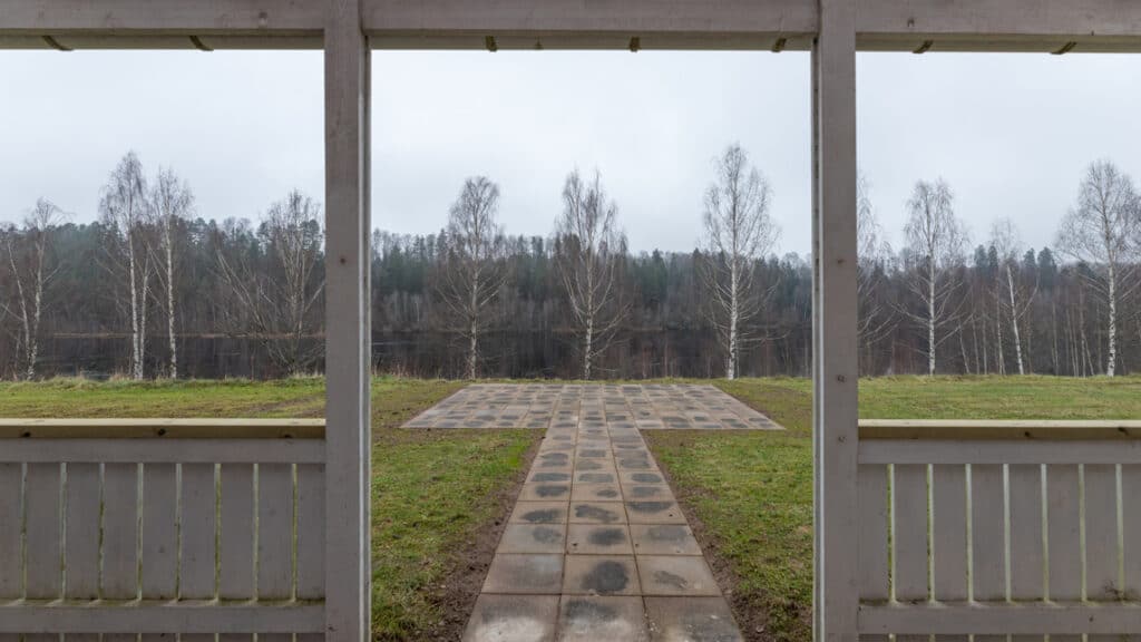 En stenlagd gångväg mellan två paviljonger i en park.