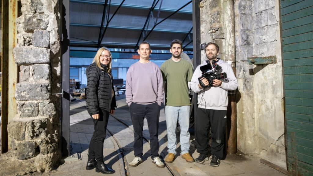 En grupp människor står en en rustik inomhusmiljö.