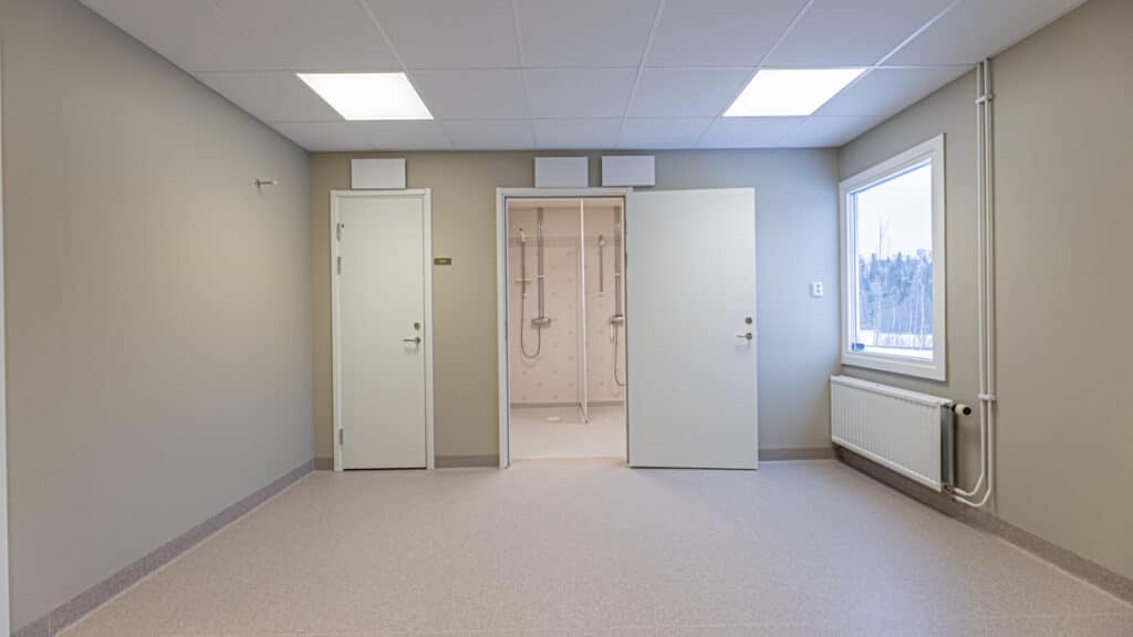 Ett tomt rum med två dörrar och ett fönster.